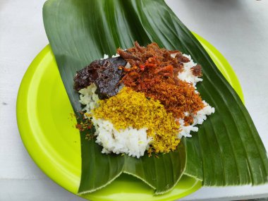 Üstünde yaprak olan bir tabak nasi pecel yemeği. Yemekler et ve sebzelerin karışımı.