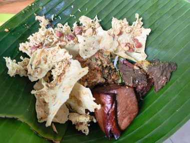 Üstünde yaprak olan bir tabak nasi pecel yemeği. Yemekler et ve sebzelerin karışımı.