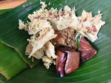 Üstünde yaprak olan bir tabak nasi pecel yemeği. Yemekler et ve sebzelerin karışımı.