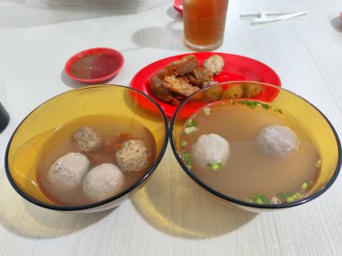 İçinde köfteler olan iki kase Bakwan Malangsoup. Bir kase sarı, diğeri kırmızı.