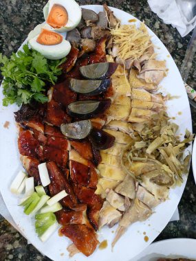 Çeşitli et, yumurta ve sebzelerle dolu bir tabak yemek. Tabak beyazdır ve çeşitli renk ve dokulara sahiptir.