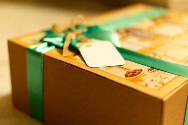 Canlı İslami sanat eserleri, develer, palmiye ağaçları ve cami elementleriyle süslenmiş bayram mübarek hediye kutusunun sergilenmesi. Kutu yeşil saten bir kurdele ve altın aksanla bağlanmış. Yanında da boş bir hediye etiketi var..