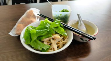 İçinde erişte ve çorba olan bir tabak yemek. Sahne davetkar ve sıcak.