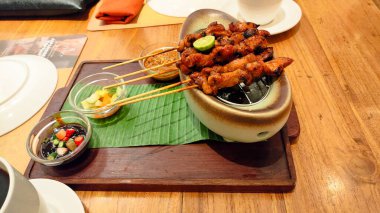 Sos soslu bir tabak et şişi. Tabak ahşap bir tahtanın üzerinde ve etrafı yemek çubuklarıyla çevrili.