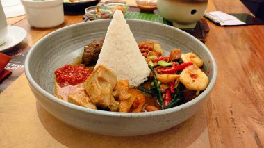 Üzerinde bir sürü farklı şey olan bir tabak yemek. Tabak masanın üstünde ve masanın üzerinde bir peçete var.