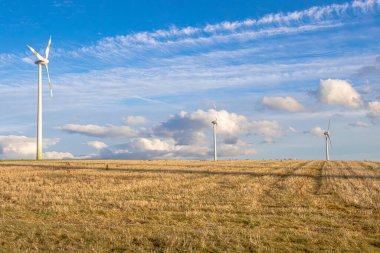 Wind turbines spin gracefully in an open field, blending technology with nature. This renewable energy source symbolizes sustainability, clean power, and a commitment to a greener, more eco-friendly future. clipart