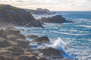 Dalgalar Breton kıyısındaki engebeli uçurumlara çarparak beyaz sprey ve ham güçle dramatik bir gösteri yaratıyor. Deniz ve taşın etkileşimi bu yabani bölgenin vahşi güzelliğini somutlaştırıyor..