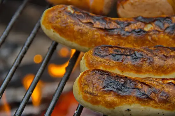 Sulu ızgara sosisler ahşap bir ızgarada cızırdıyor dumanlı aromaları havayı dolduruyor. Açık ateşte mükemmel pişmiş, ağız sulandırıcı bir yemek ve yaz ızgarası sunuyorlar.