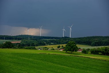 Karanlık bir hava ile yaz fırtınası yaklaşıyor ve derin mavi gökyüzünün altındaki yemyeşil alanlar üzerinde dramatik, yüksek kontrastlı bulutlar..