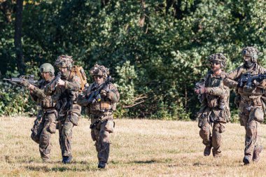 Alman Bundeswehr paraşütçüleri tüfek ve taktik teçhizatla NATO tatbikatına katıldılar. Askerler, savaş hazırlığı, takım çalışması ve acil müdahale eğitimleri sırasında yaralı yoldaşlara yardım ediyor..