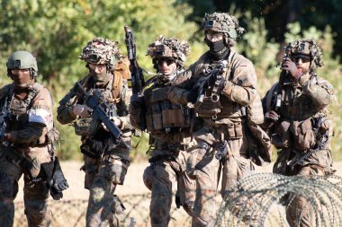 Alman Bundeswehr paraşütçüleri tüfek ve taktik teçhizatla NATO tatbikatına katıldılar. Askerler, savaş hazırlığı, takım çalışması ve acil müdahale eğitimleri sırasında yaralı yoldaşlara yardım ediyor..