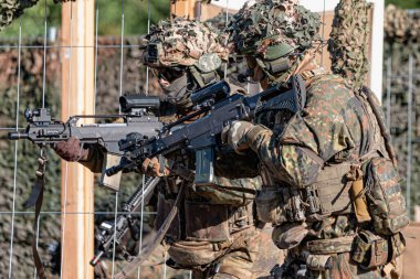 Alman Bundeswehr paraşütçüleri tüfek ve taktik teçhizatla NATO tatbikatına katıldılar. Askerler, savaş hazırlığı, takım çalışması ve acil müdahale eğitimleri sırasında yaralı yoldaşlara yardım ediyor..