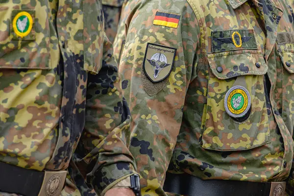 Alman Bundeswehr paraşütçüleri bir NATO etkinliğinde tüfek ve tam teçhizat taşıyarak sıraya girdiler. Üniformaları ve silahları disiplini, hazır olmayı ve uluslararası askeri işbirliğinin gücünü yansıtıyor..