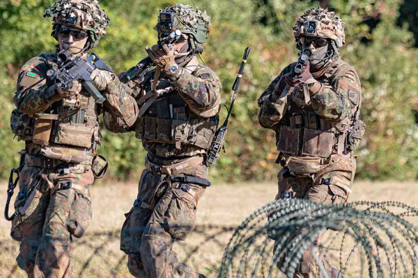 Alman Bundeswehr paraşütçüleri tüfek ve taktik teçhizatla NATO tatbikatına katıldılar. Askerler, savaş hazırlığı, takım çalışması ve acil müdahale eğitimleri sırasında yaralı yoldaşlara yardım ediyor..