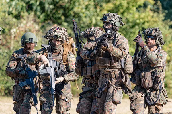 Alman Bundeswehr paraşütçüleri tüfek ve taktik teçhizatla NATO tatbikatına katıldılar. Askerler, savaş hazırlığı, takım çalışması ve acil müdahale eğitimleri sırasında yaralı yoldaşlara yardım ediyor..