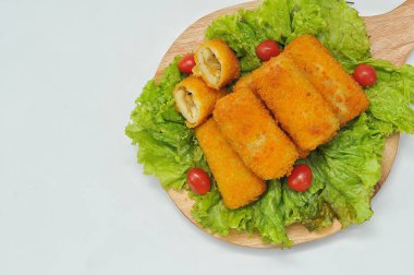 marul yaprakları ve ahşap bir tabanda servis edilen risol.