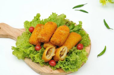 marul yaprakları ve ahşap bir tabanda servis edilen risol.