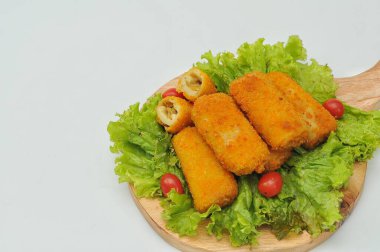 marul yaprakları ve ahşap bir tabanda servis edilen risol.