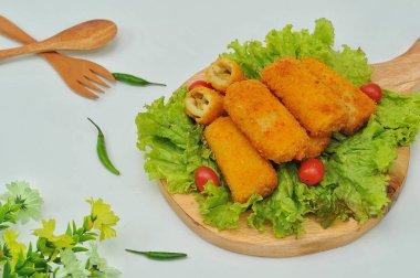 marul yaprakları ve ahşap bir tabanda servis edilen risol.