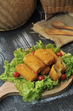 marul yaprakları ve ahşap bir tabanda servis edilen risol.