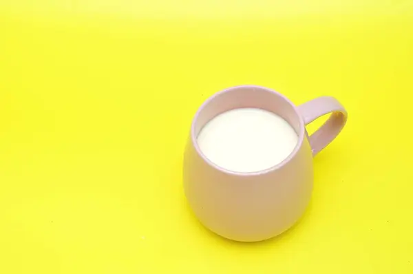 milk in a glass, yellow background