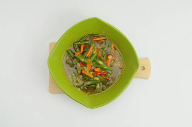 Kızarmış yeşil fasulye ve havuç, ahşap bir masada yeşil bir kasede servis edilir.