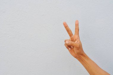 Kadın eli beyaz arka planda barış işareti yapıyor.