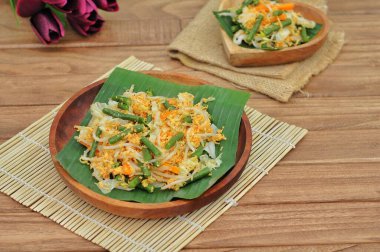 Seçici odaklı Urap Sayur Endonezya geleneksel yemeğidir. Baharatlı ve baharatlı, muz yaprağı ve ahşap tabakta servis edilen çeşitli sebzelerden oluşan bir salata tabağı.
