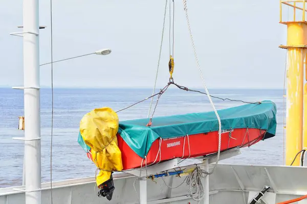 ロープに掛かっている防水シートが付いている覆われた救命ボート — ストック写真