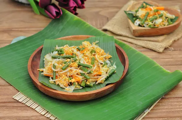 選択的な焦点Urap Sayurはインドネシアの伝統的な食べ物です 味付けとスパイスに混ぜた様々な野菜のサラダ料理 バナナの葉と木製のプレートで提供 — ストック写真