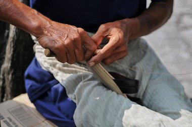  Bir adamın elleri sandalet dikiyor.