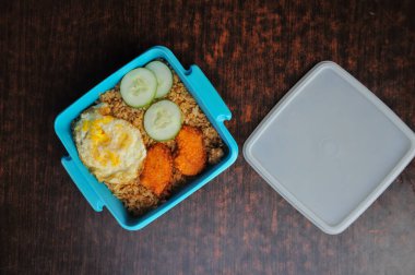 Kızarmış pirinç, nugget ve yumurta içeren yemek kutusu.