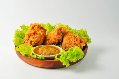 Yeşil marullu kızarmış tavuk, ahşap tabakta servis ediliyor, izole edilmiş beyaz arka plan.