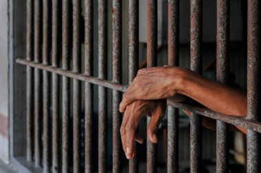 Hapisteki parmaklıkları tutan eller.