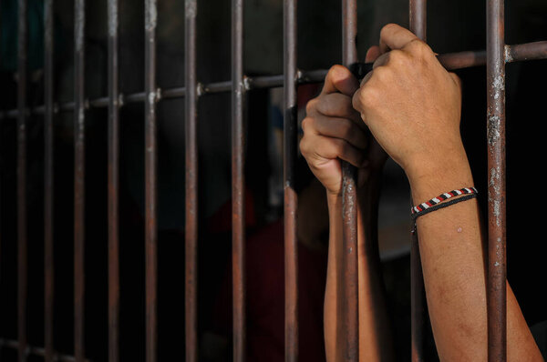 woman hand holding the barbed wire in the prison