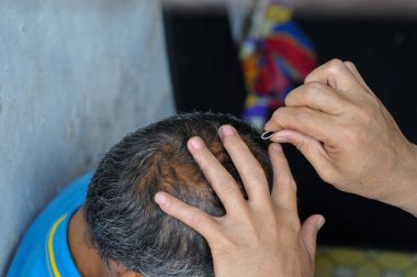 Bir adamın eli arkadaşının gri saçlarını çekiyor.