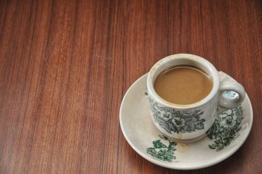 Tahta bir masada bir fincan sıcak kahve.