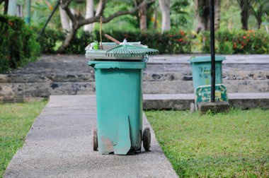 Park yolunda yeşil plastik çöp tenekesi