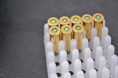 Birkaç parlak, boş mermi kovanı detaylı bir şekilde yakın plan çekimde gösteriliyor. Beyaz plastik bir tepside dikiliyorlar.. 