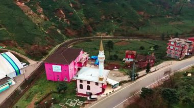 Merkez, Rize, Türkiye - Pembe bir bina ve beyaz bir camii olan küçük bir kasabanın 4 Mart 2024 'te Bustling City Ana Yolu ve Sakin Sahil Tarafı' na Kuş Gözü Bakışı