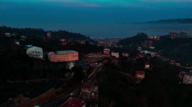 Merkez, Rize, Türkiye - 5 Mart 2024 'te Fırıl fırıl yanan kentin arka planında bir dağ bulunan bir şehrin hava gece görüşü