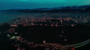 Merkez, Rize, Türkiye - 5 Mart 2024 'te Gece Vaktinde Hareketli Şehir' e Kuş Gözü Bakışı Arkasında dağ bulunan bir şehrin havadan görünüşü