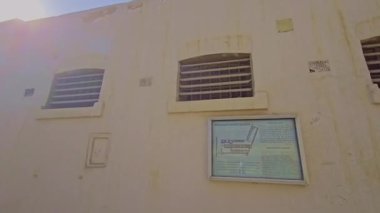 Caddede yürüyen bir adam binanın önünden geçiyor.