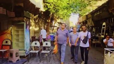 Sandalyede oturan bir adamla sokak sahnesi.