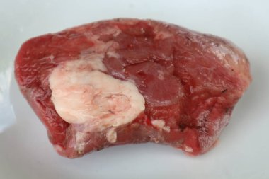 Beyaz bir yüzeyde bir et parçası gösterilir..