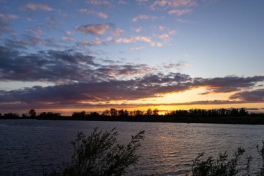 Biesbosch Milli Parkı 'nda güzel kırmızı bir akşam gökyüzü manzarası ve bir su kütlesi