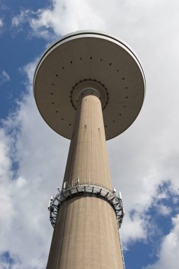 Mavi gökyüzüne karşı Kiel şehrindeki uzun televizyon kulesi. Aşağıdan bak. Beton ayaklı kocaman bir tabak..