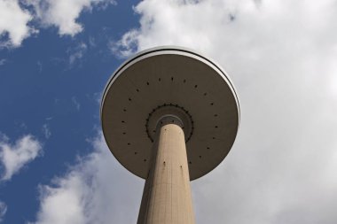 Mavi gökyüzüne karşı Kiel şehrindeki uzun televizyon kulesi. Aşağıdan bak. Beton ayaklı kocaman bir tabak..