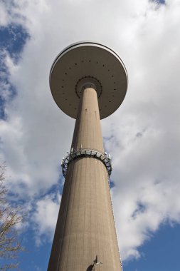 Mavi gökyüzüne karşı Kiel şehrindeki uzun televizyon kulesi. Aşağıdan bak. Beton ayaklı kocaman bir tabak..