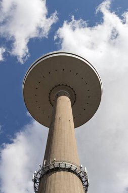 Mavi gökyüzüne karşı Kiel şehrindeki uzun televizyon kulesi. Aşağıdan bak. Beton ayaklı kocaman bir tabak..
